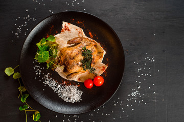 Grilled whole chicken vith vegetables on black background