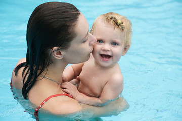 Mother and baby enjoying the day at the pool, summer outdoor activity, learning to swim