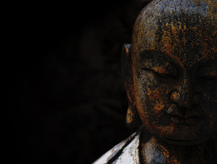 Rock Buddha statue with black background used for amulets of Buddhism religion. Buddhism is popular region in China Japan and south east Asia.copy space concept.