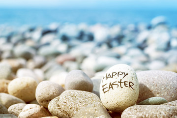Easter egg from a stone with the inscription Happy Easter on the sea pebble beach.