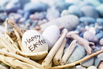 Easter egg from a stone with the inscription Happy Easter in a decorative nest from brushwood on...
