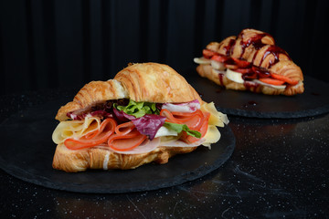 Luxury restaurant croissant stuffed with salad, vegetables, cheese, meat and egg