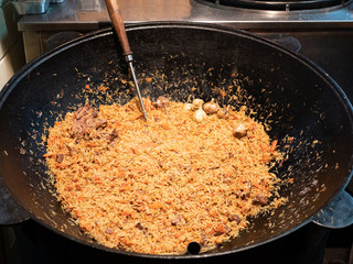 traditional chinese street food pilaf with meat in large pan cauldron