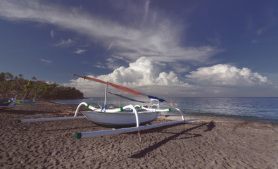 Catamaran on a sandy seashore with sun and clouds