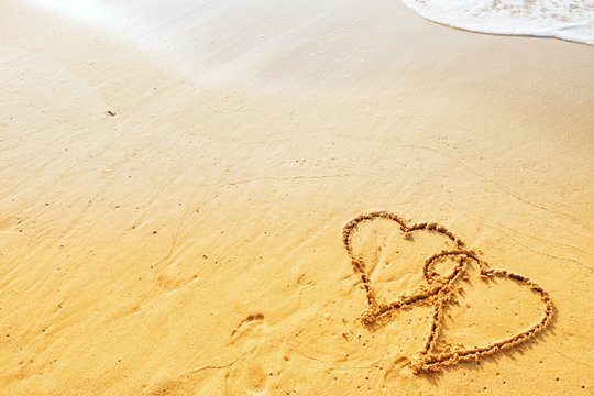 Valentine's day concept, two heart shape writing on sand beach with waves ocean.