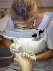 Female chiropodist working on a senior clients feet.