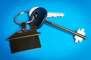 keys to the house with a keychain in the shape of the house.
