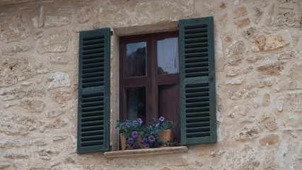 Fototapeta na wymiar Fenster mit Fensterläden und Blumentöpfen auf Mallorca