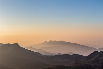 Sunrise view over mountains from a mountain peak. Mountains silhouette.  Blue and orange sky. Misty morning. Nature landscape.