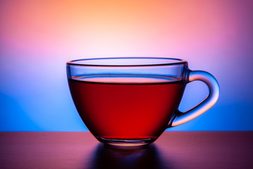  Glass transparent cup with a drink on a bright multi-colored background.