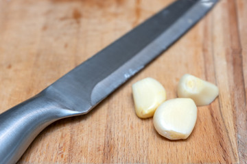 3 cloves of garlic lying on the Board next to the knife