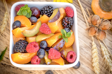 Fruit salad in white bowl on rustic table