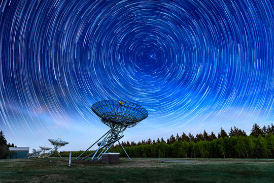 The Westerbork Synthesis Radio Telescope (WSRT) during dusk, with a light cloudy sky and stars a little visible