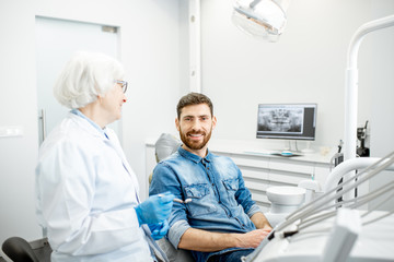 Obraz premium Portrait of a handsome male patient in blue shirt with elderly woman dentist in the dental office