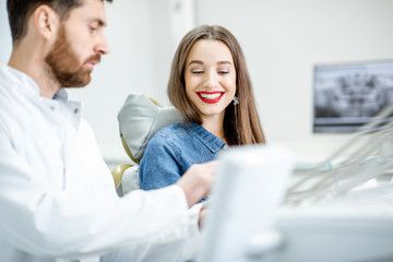 Young beautiful woman during the medical consultation with male dentist in the dental office