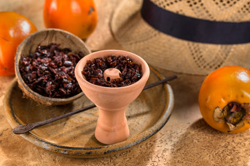 Hookah in a clay bowl for Smoking hookah with persimmon fruit in the background.