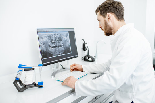 Dentist Looking On The X-ray Of A Jaw Working With A Computer In The Dental Office