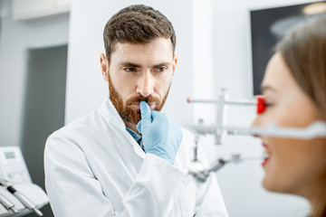 Portrait of a thoughtful dentist during the work with young woman patient in the dental office