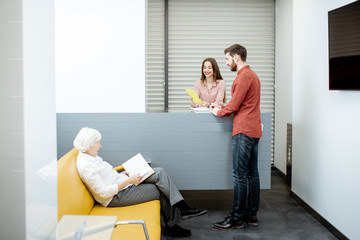 Modern hospital reception with senior woman and man waiting for the doctor