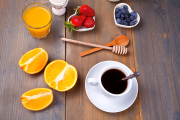 Cup of coffee and fruits, berries, milk and juice on the wooden background. Top view.