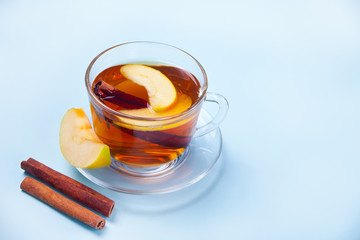 Drink of apple tea with cinnamon stick, star anise and clove. Seasonal punch in cup on the blue...