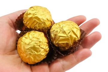 Hand Holding Round Chocolate Candies in Gold Package