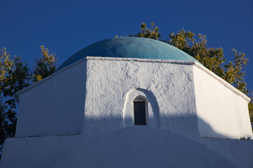 traditional narrow street in Mykonos with blue doors and white walls