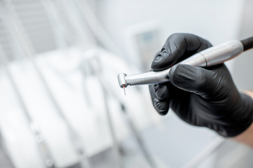 Close-up of a dental drill with nozzle in the hands in black medical gloves