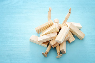 wooden dummy buried under stack of domino blocks asking for help. concept of stress, trouble and...