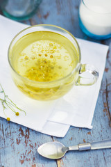Fresh chamomile blossom tea in a glass cup on a wooden table, healthcare and healthy eating concept