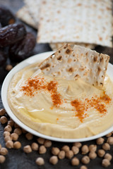 Close-up of creamy hummus with matzo and dates, selective focus, vertical shot