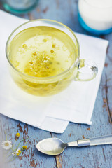 Fresh chamomile blossom tea in a glass cup on a wooden table, healthcare and healthy eating concept