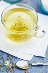 Fresh chamomile blossom tea in a glass cup on a wooden table, healthcare and healthy eating concept
