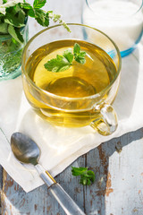 Fresh mint leaf tea in a glass cup on a wooden table, healthcare and healthy eating concept