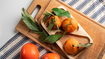 Ripe persimmon and tangerines on a branch on a white background