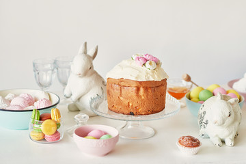 Easter sweet bread, Easter cake and multi-colored eggs with tulips and a white rabbit. Holidays breakfast concept with copy space. Retro style in tones. Easter greeting card template