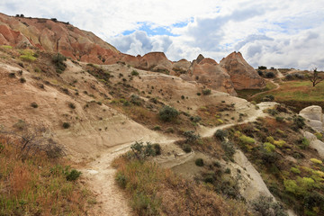Fototapeta na wymiar A winding mountain trail passes between huge and old stones in the Cappadocian red valley.