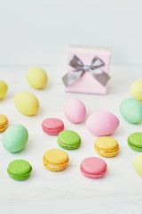 Spring and Easter holiday concept with copy space. Template Easter Greeting Card. Easter decoration with eggs and gift box. Macarons with Easter eggs background