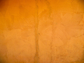 Orange wall with rustic texture made with mortar and some cracks