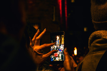 Fototapeta na wymiar Woman taking pictures with her phone at the torchlight procession preceding new years eve or Hogmanay in Edinburgh Scotland 