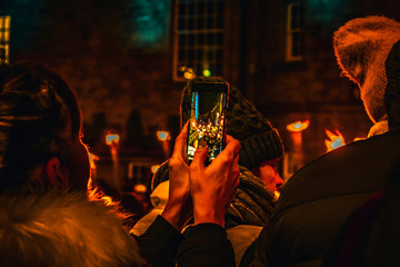 Woman taking pictures with her phone at the torchlight procession preceding new years eve or Hogmanay  in Edinburgh Scotland 