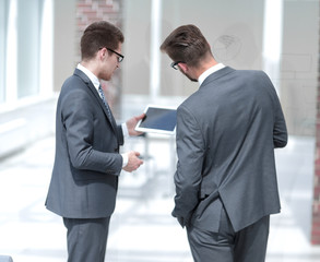 two businessmen reading a message on a digital tablet