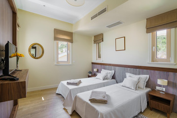 Fototapeta na wymiar Interior of a spacious light bedroom with windows in a luxury villa. Big comfortable double bed in elegant modern bedroom