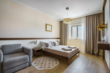 Interior of a spacious light bedroom with windows in a luxury villa. Big comfortable double bed in elegant modern bedroom