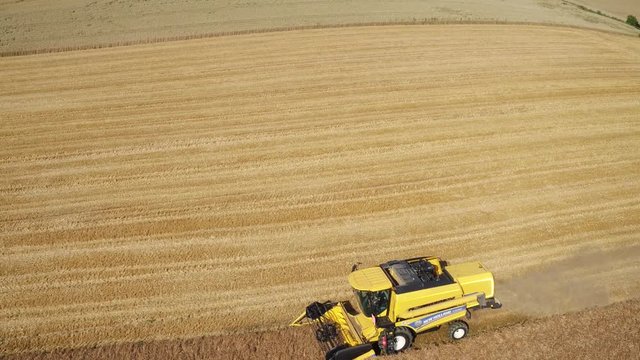 Aerial of a yellow combine harvester in a beautiful golden wheat field as it harvests on a bright sunny day in bavaria germany 