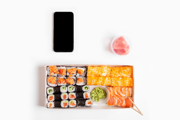 sushi set rolls on white background chopsticks wasabi ginger phone delivery food