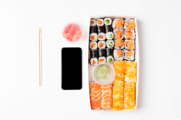 sushi set rolls on white background chopsticks wasabi ginger phone delivery food