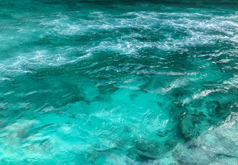 clear blue transparent blue sea water with splashing foam from running boat.