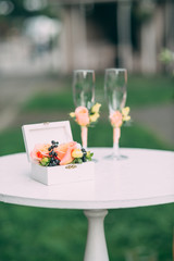Two wedding glasses and bridal bouquet on stone in summer garden