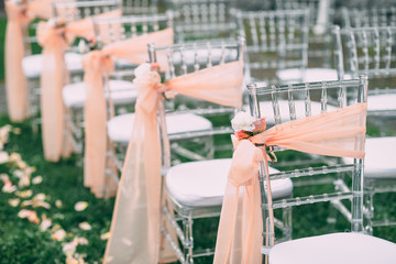 Square wedding ceremony. Transparent chairs are decorated with flowers, greenery. Cute, trendy...